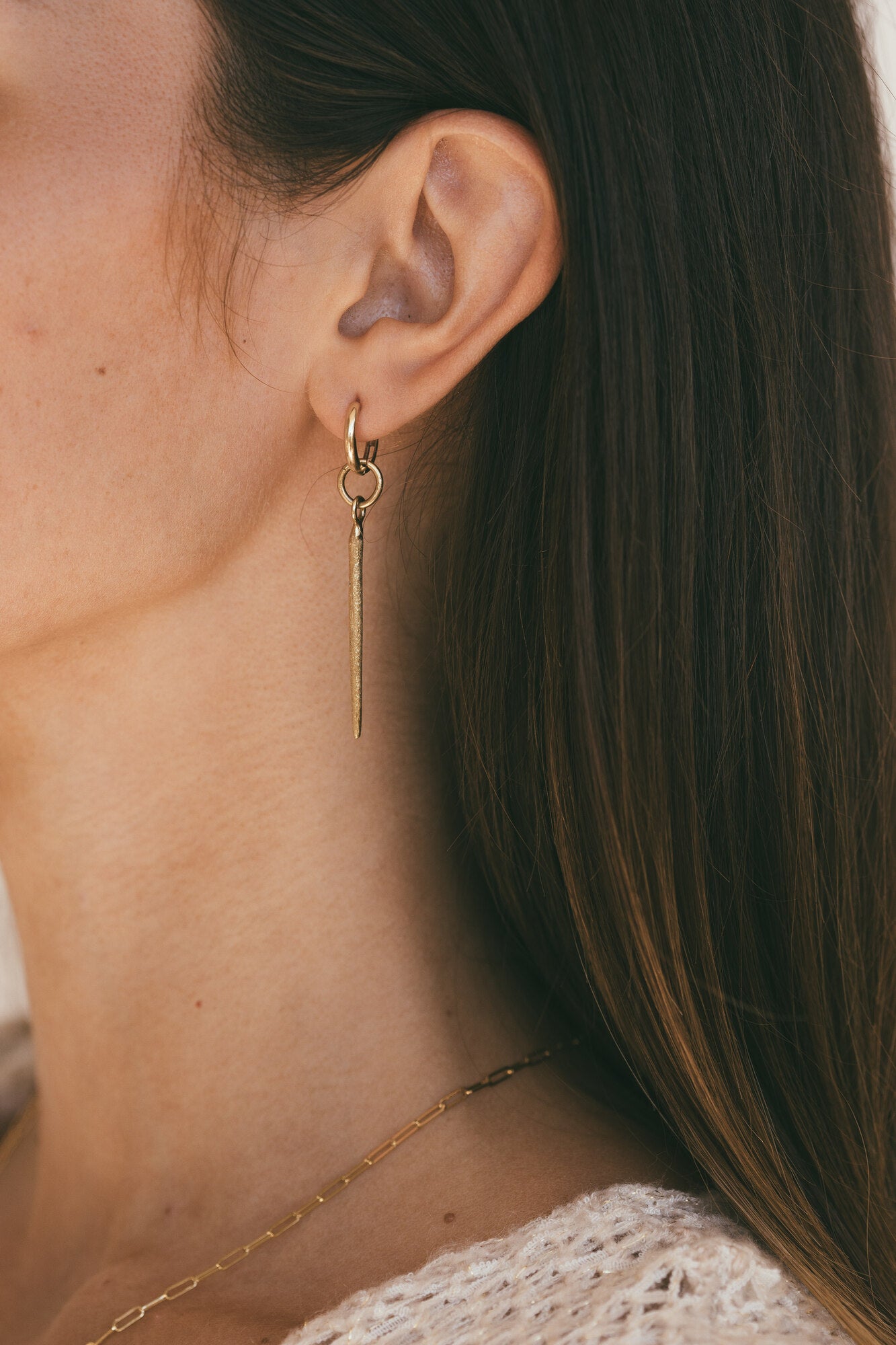 Model looking to the side with gold sea urchin earrings