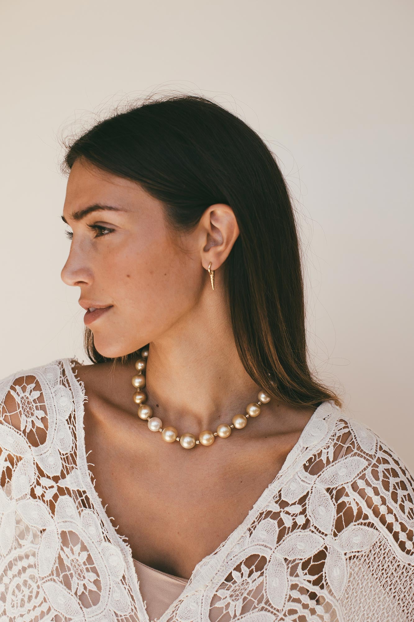 Model wearing earrings with pearl choker